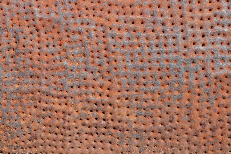 An image of a piece of rusty iron covered in many small holes.