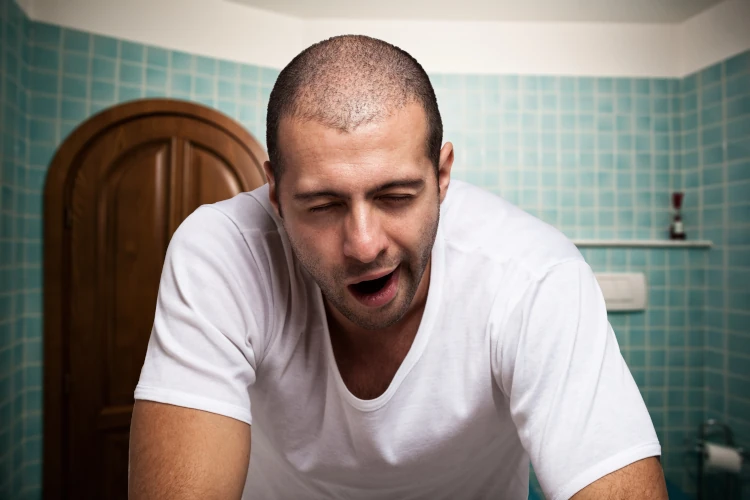 A man with thin hair yawning and looking tired.