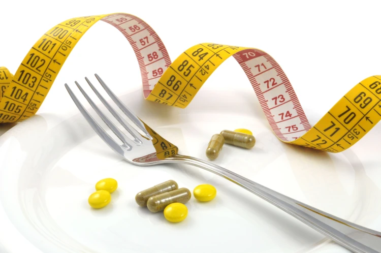 Measuring tape with a fork and food supplements.