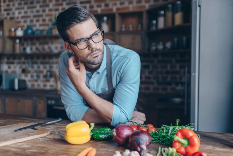 A man with an apron and cutting board getting ready to prepare some vegetables.